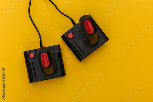 Two retro joysticks on yellow background. Gaming, video game competition. Top view, minimalism