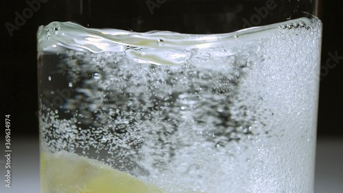 Lemon wedge being dropped from top of frame into a glass of carbonated water - SLOW MOTION 240 frames per second (240p 240fps) - Shot in 2K exported as 1080p photo