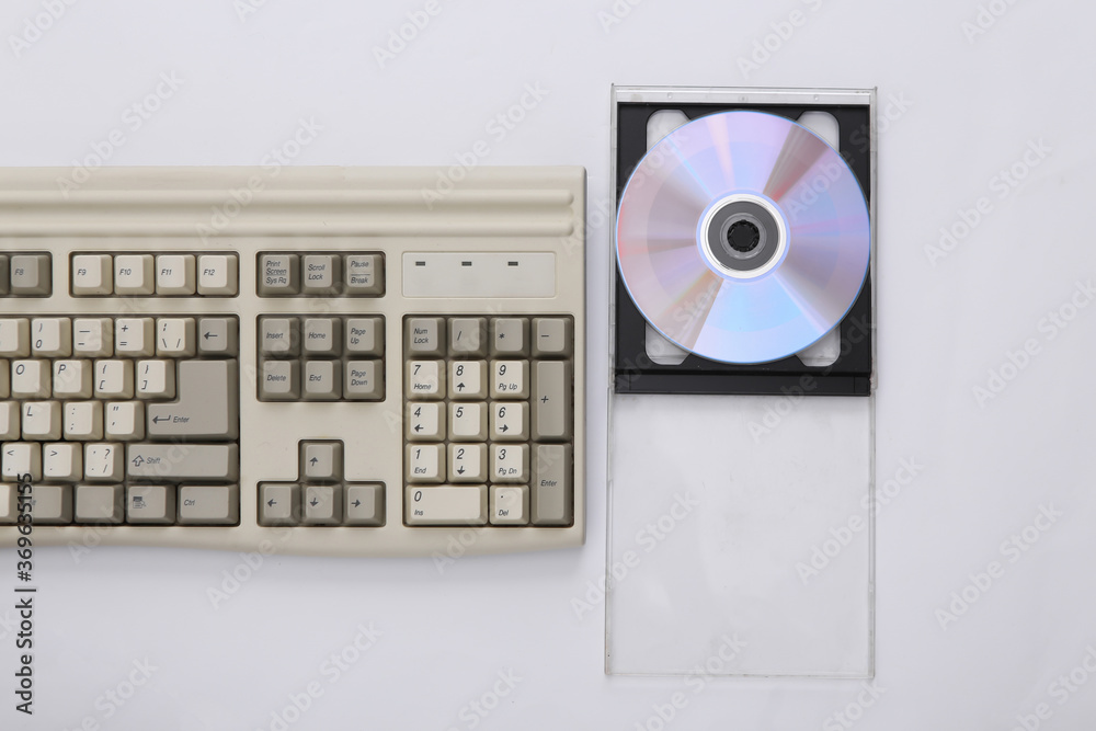 Retro electronics, pc technology 90s. PC keyboard, cd in box on white background. Top view Retro electronics, pc technology 90s. PC keyboard, cd in box on white background. Top view