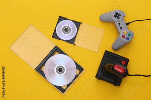 Fotografija Retro gamepad and joystick, CD's on blue yellow background