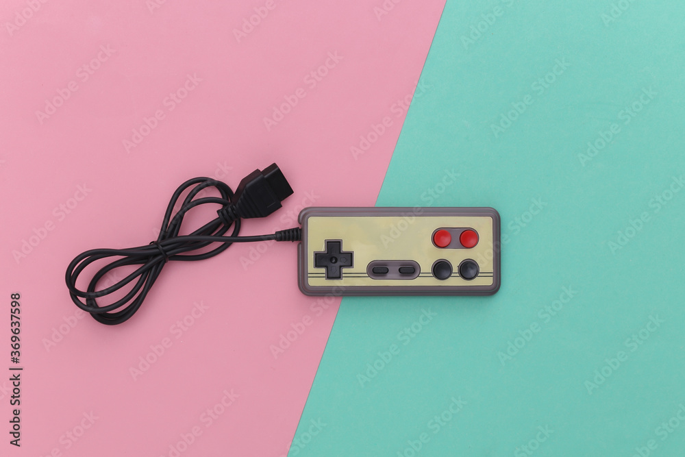 Wired retro gamepad (joystick) with wound cable on pink blue background. Video game, gaming. Top view