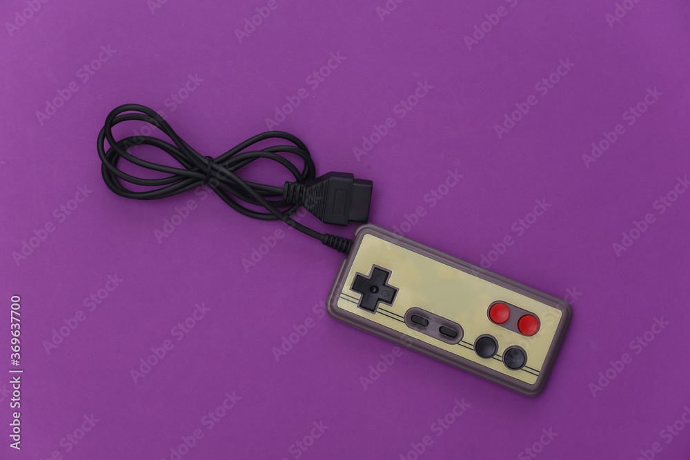 Wired retro gamepad (joystick) with wound cable on purple background. Video game, gaming. Top view Wired retro gamepad (joystick) with wound cable on purple background. Video game, gaming. Top view