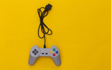 Wired retro gamepad (joystick) with wound cable on yellow background. Video game, gaming. Top view