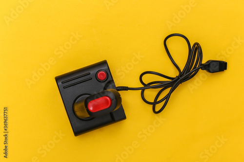 Wired retro joystick with wound cable on yellow background. Video game, gaming. Top view