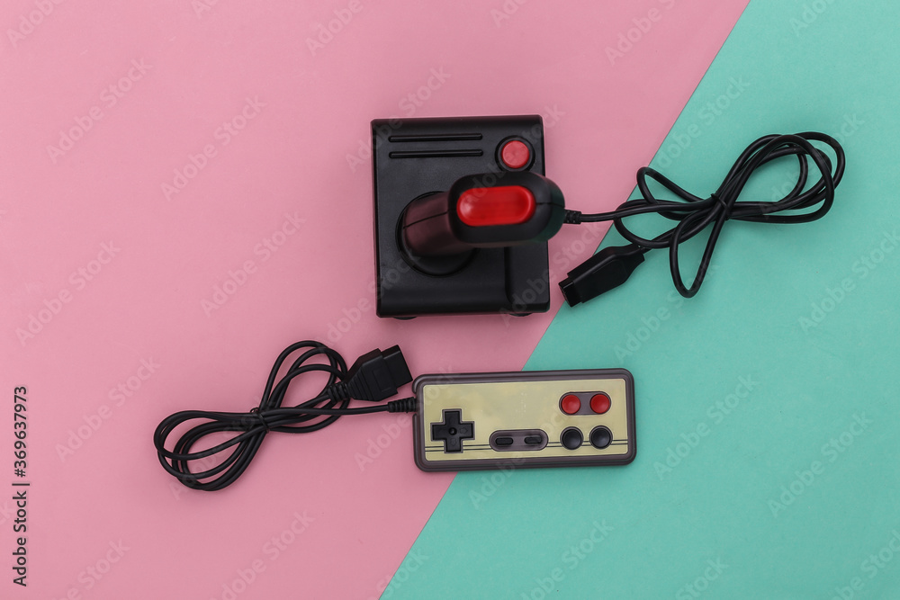 Wired retro gamepad and joystick with wound cable on pink blue background. Video game, gaming. Top view Wired retro gamepad and joystick with wound cable on pink blue background. Video game, gaming. Top view