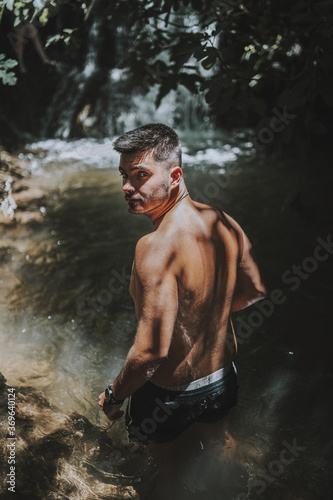 Young male relaxing near the Hueznar waterfall in the Sierra Norte natural park in Spain photo