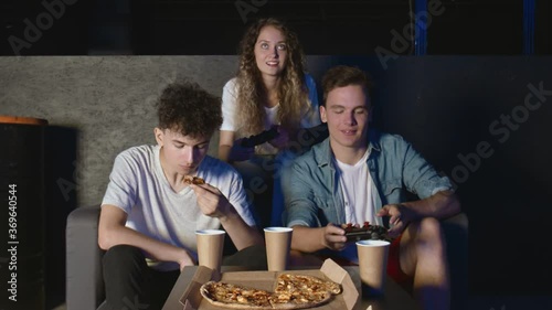 Young friends finished play game console and start eaing pizza in dark room. photo