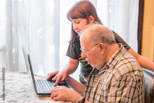 Foto granddaughter is helping her grandfather to use a pc