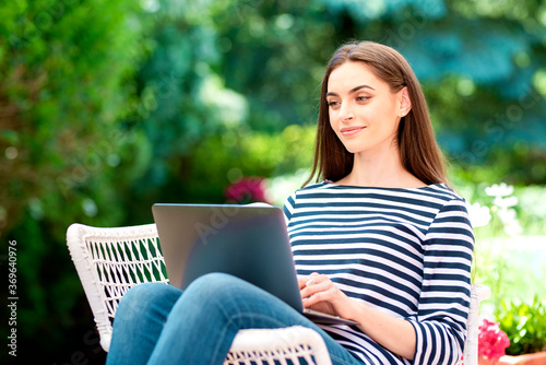 Attractive woman working on laptop in the garden at home