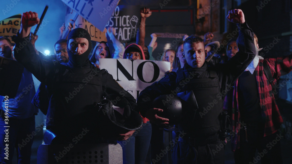 Black lives matter. Two cops support the protest holding their helmets strike among group of activists. Multi-ethnic protesters rebel against violence, inequality, racism. Black lives matter. Two cops support the protest holding their helmets strike among group of activists. Multi-ethnic protesters rebel against violence, inequality, racism.