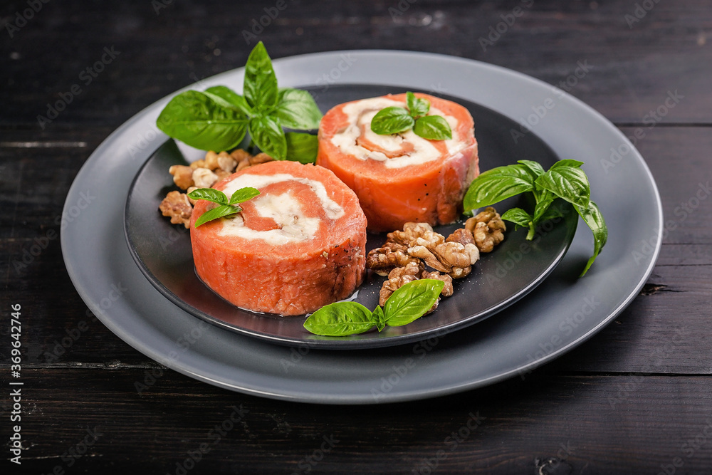 Salmon rolls with cream cheese, walnuts and fresh basil on a dark wooden background. Delicious and healthy seafood. Salmon rolls with cream cheese, walnuts and fresh basil on a dark wooden background. Delicious and healthy seafood.