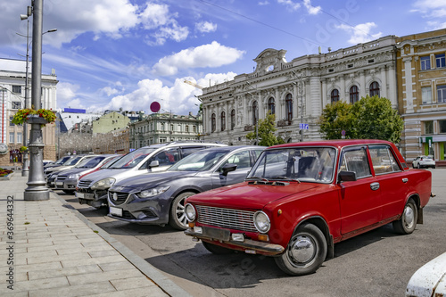 Red VAZ-2101 on the Constitution Square in Kharkiv (Ukraine), close-up. A row of cars parked on the street against the background of ancient buildings