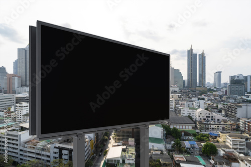 Blank black road billboard with Bangkok cityscape background at day time. Street advertising poster  mock up  3D rendering. Side view. The concept of marketing communication to promote or sell idea.