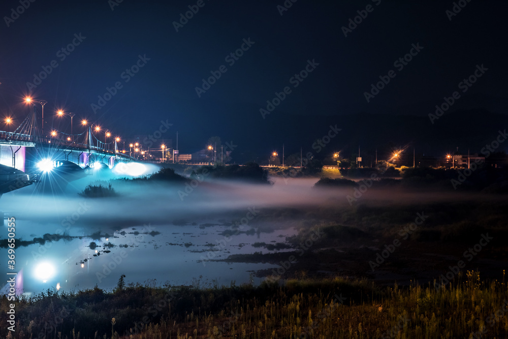The beautiful dense foggy nightscape with bridge and lanterns light in the night.