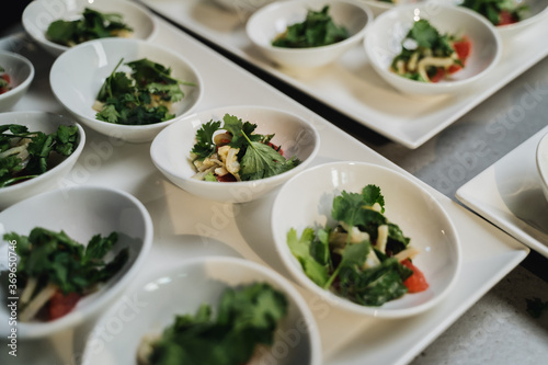 Detalle de catering con platos individuales de ensalada encima de una mesa