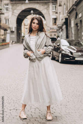 Young girl in white clothes goes on a street. Street style. Soft selective focus.