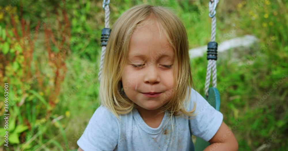 Preschooler playing on a swing in the garden Preschooler playing on a swing in the garden