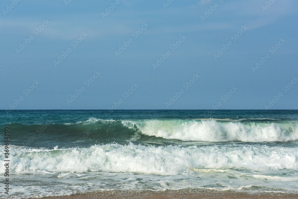 The big breaking waves during a strom at the beautiful summer sea shore background the blue sky and horizon