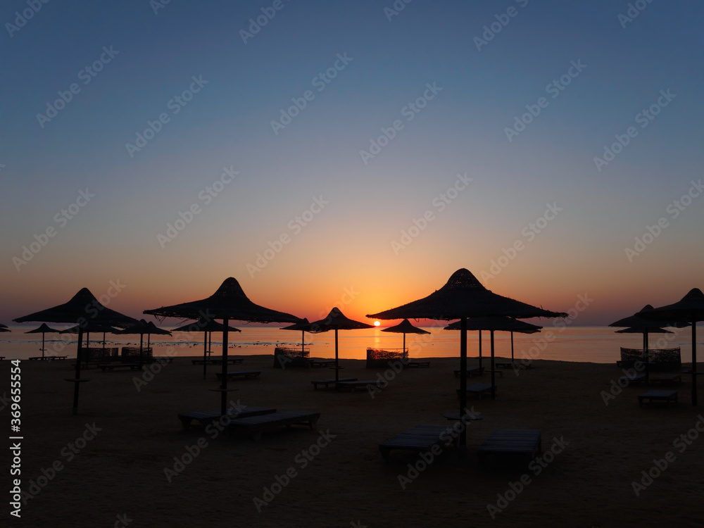 Beach umbrella  silhouette at sunrise, tropical sea landscape