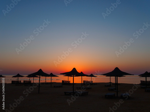 Beach umbrella silhouette at sunrise, tropical sea landscape