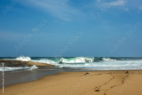 The huge waves crashing into ston island against the blue sky and horizon at summer sea shore.