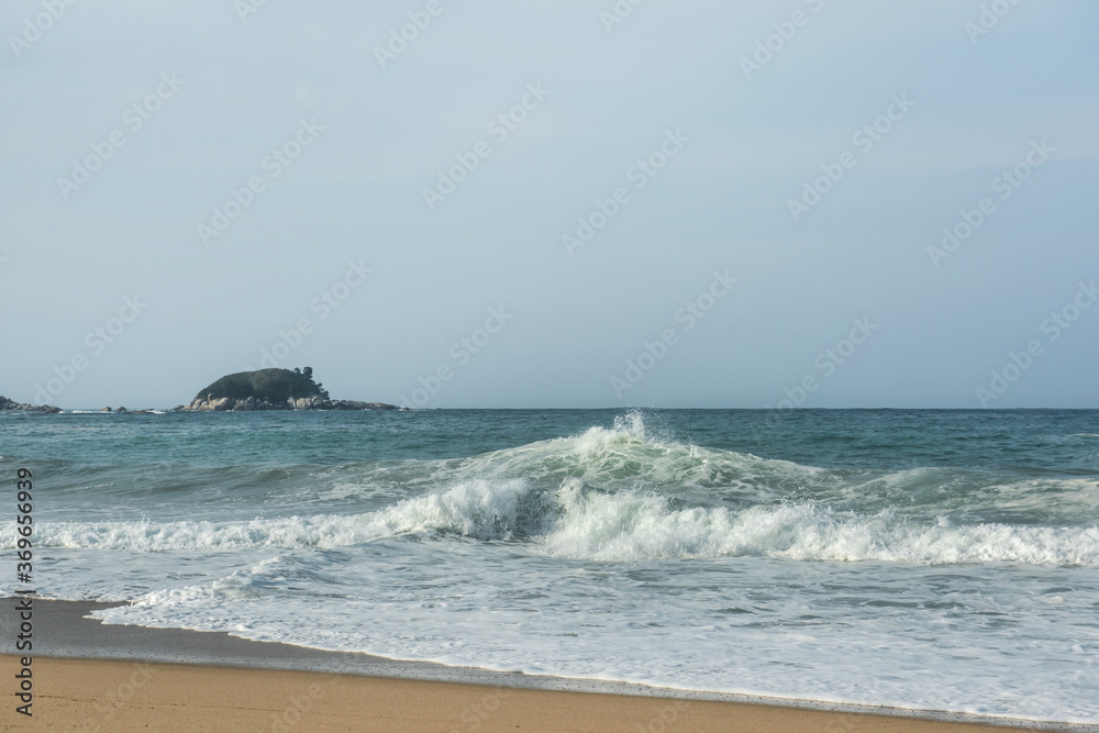 The huge waves crashing into ston island against the blue sky and horizon at summer sea shore. The huge waves crashing into ston island against the blue sky and horizon at summer sea shore.