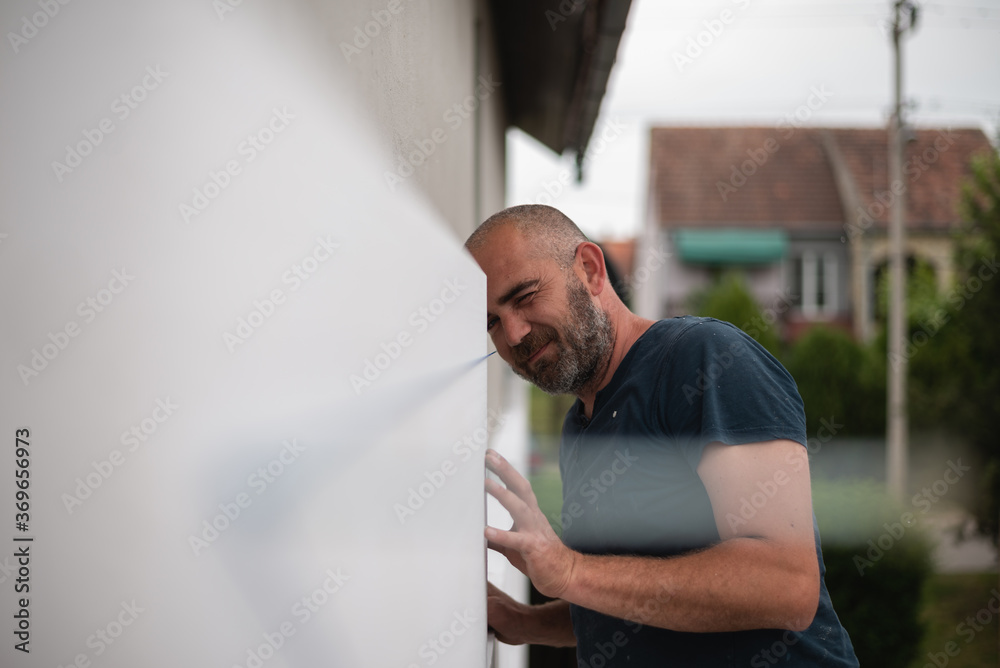 Construction worker working on a house facade checking level Construction worker working on a house facade checking level