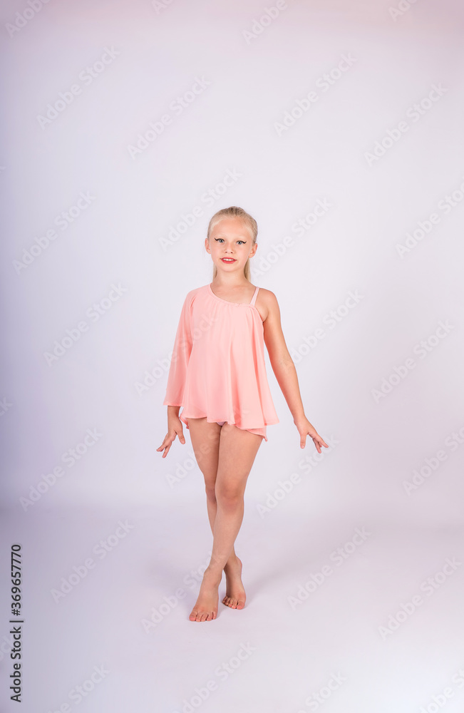 a beautiful gymnast girl in a sports swimsuit stands on a white isolated background and looks at the camera a beautiful gymnast girl in a sports swimsuit stands on a white isolated background and looks at the camera