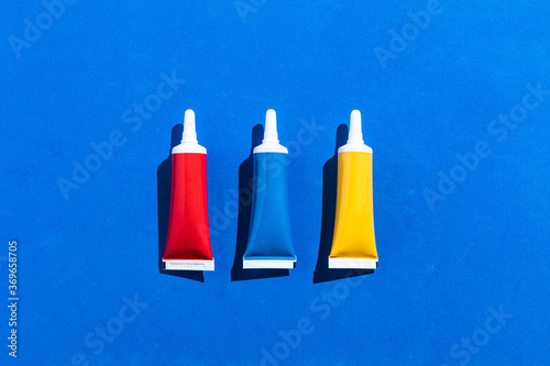 Three tubes of red  blue and yellow color from above on blue background