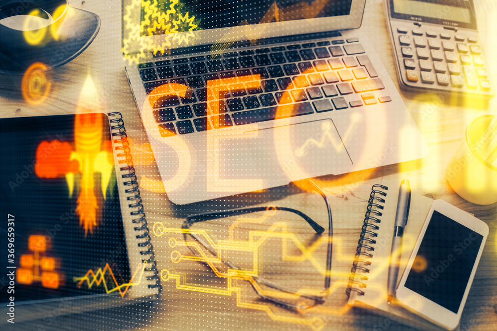 Double exposure of table with computer and seo drawing hologram. Search optimization concept.