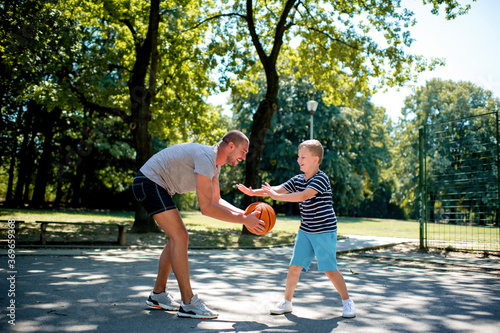 Cute blond boy practicing basketball with his coach