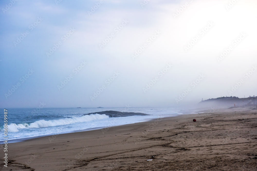 The huge waves crashing into ston island against the blue sky and horizon at summer sea shore.