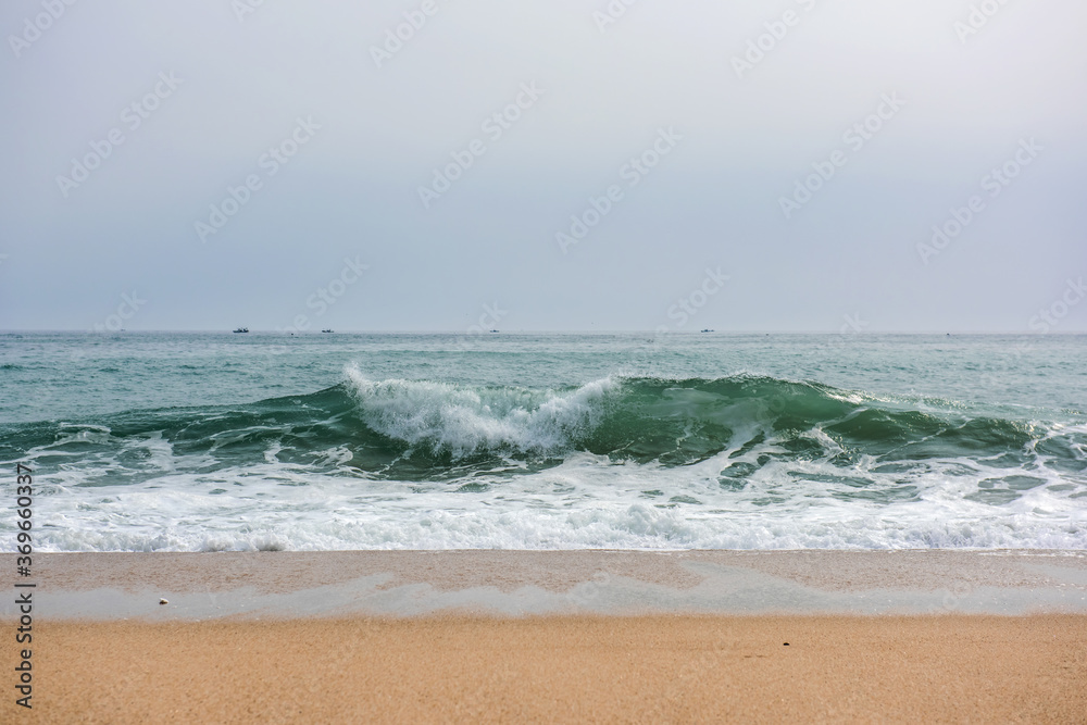 The huge waves crashing into ston island against the blue sky and horizon at summer sea shore.