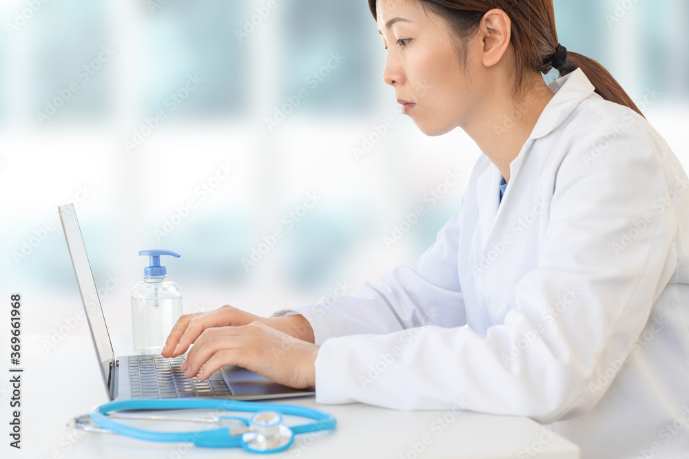 concentrated asian female doctor typing on laptop in clinic office, hospital physician lifestyle . concentrated asian female doctor typing on laptop in clinic office, hospital physician lifestyle .
