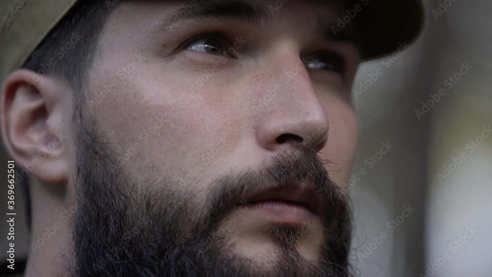 Obraz premium Portrait of handsome young man hunter or tourist. Man in camouflage clothes hunts outdoor in forest hunting alone. Close up of man hiker standing in forest. Hunter hunts down prey