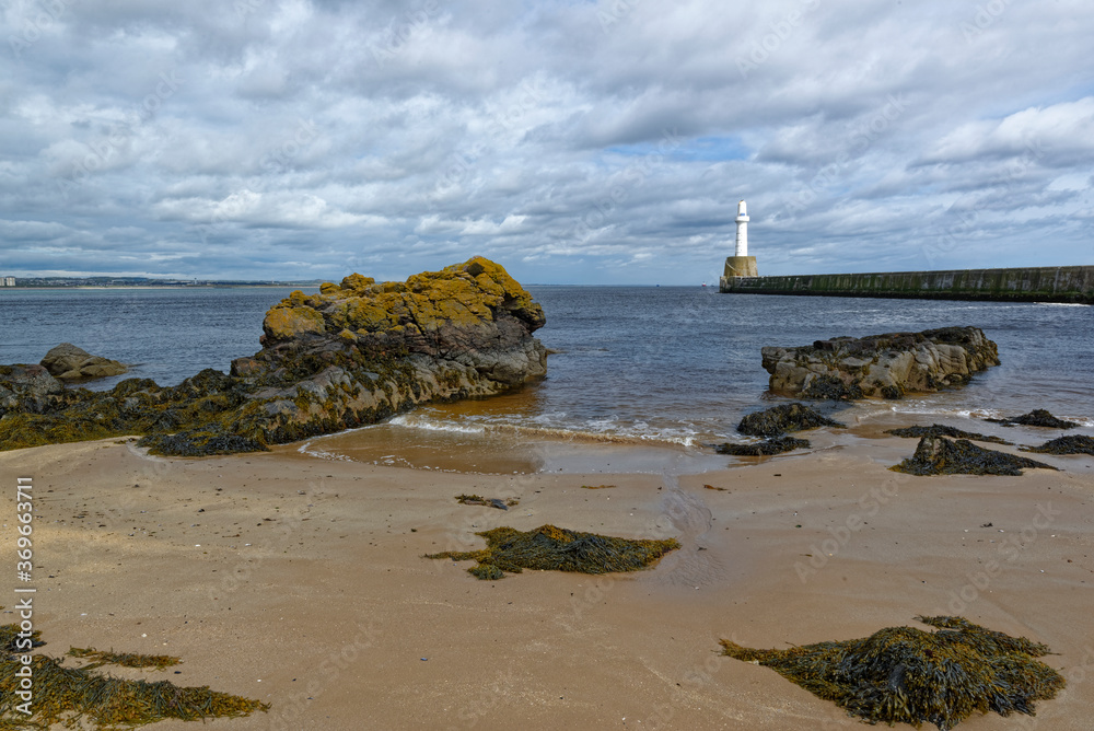 The small sandy beach with its exposed rocks at Low tide beside the Southern Breakwater of Aberdeen Harbour's entrance. The small sandy beach with its exposed rocks at Low tide beside the Southern Breakwater of Aberdeen Harbour's entrance.