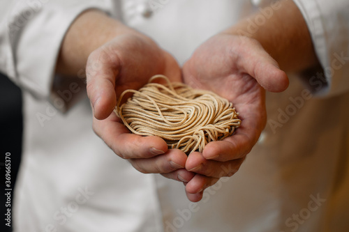 Chef holding homemade raw brown buckwheat noodles 