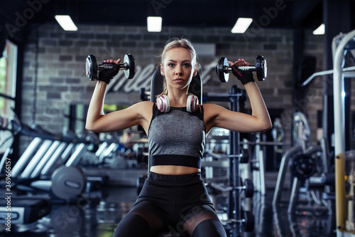 Beautiful fitness woman with lifting dumbbells .