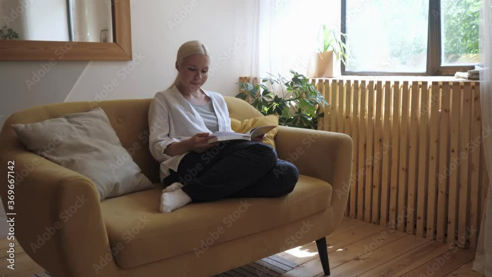Young beautiful woman reading book at home sitting on a yellow sofa Young beautiful woman reading book at home sitting on a yellow sofa