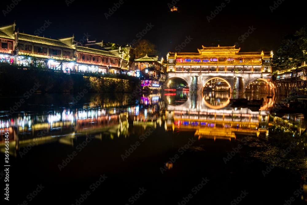 View of illuminated at night riverside houses in ancient town of Fenghuang known as Phoenix, China