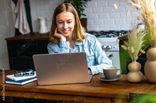 Smiling woman with laptop in kitchen at home