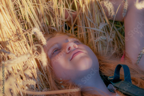 Girl lying in a straw among wheat-land