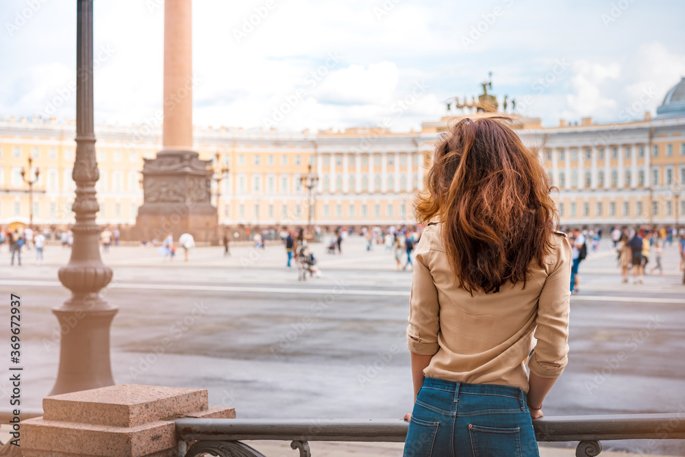 A beautiful woman with long hair visits the tourist city of Saint Petersburg while staying at the main attraction on the Palace square in the center