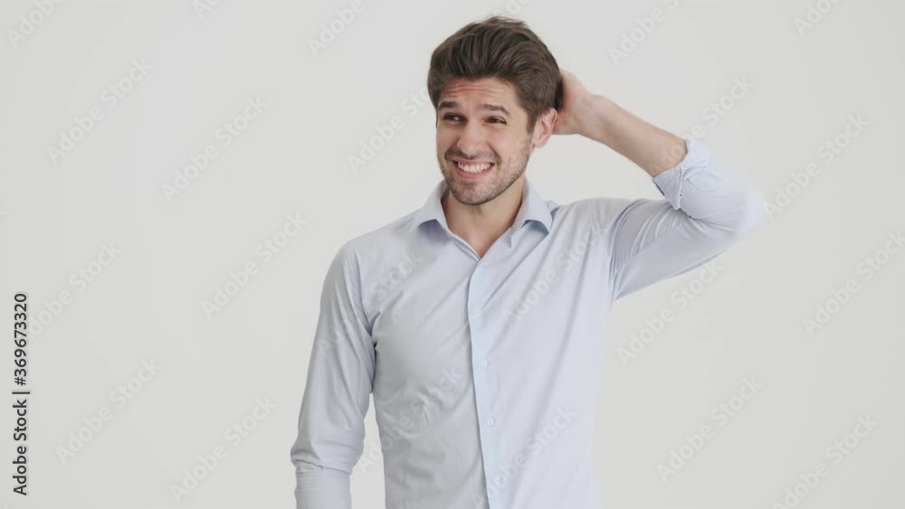 A confused man is shrugging shoulders while raising hands standing isolated over white background A confused man is shrugging shoulders while raising hands standing isolated over white background