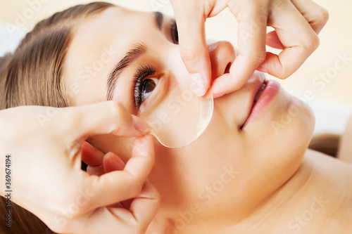 Beautician in spa salon applying under eye patches client Fototapeta