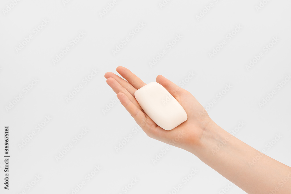 Naklejka premium Bar of white soap in a woman's hand.