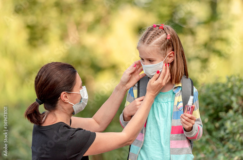 Mother putting mask on daughter before school photo