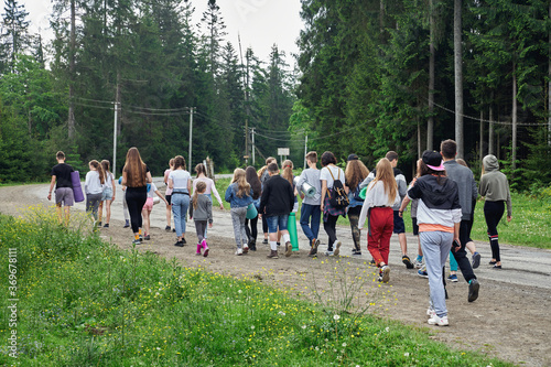 Teens walking through wet spruce forest road.