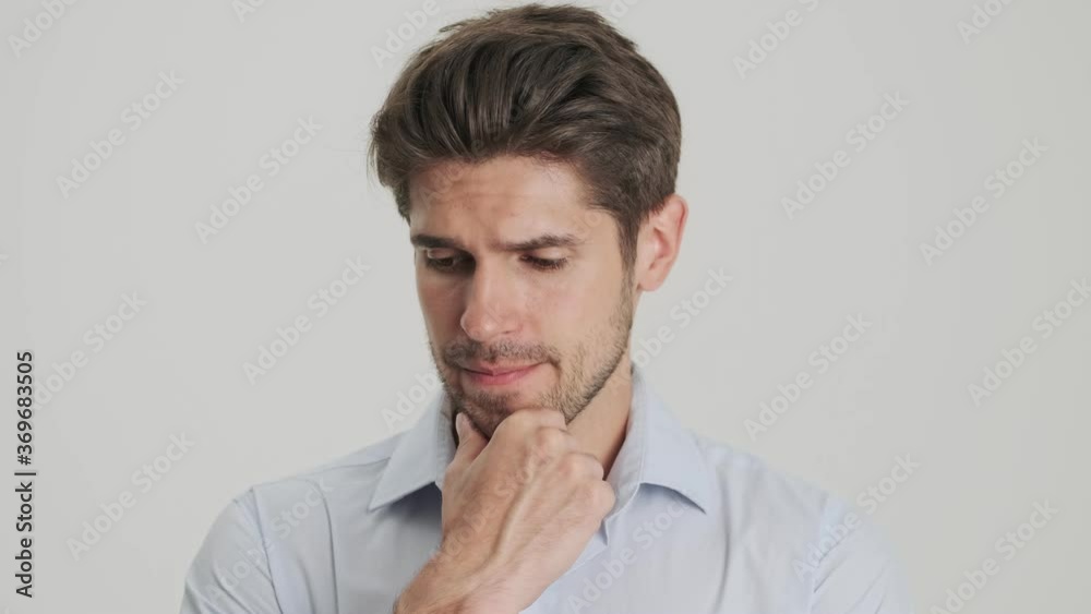 A close-up view of a serious young man is thinking about something isolated over white background