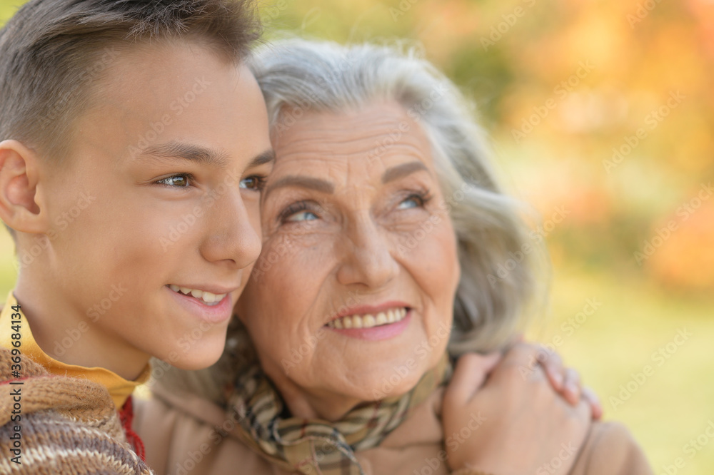 Close-up portrait of grandmother and grandson hugging in park
